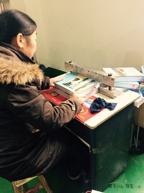 雙豐印務(wù)后工部的大姐正在進行精裝書印刷后的工序